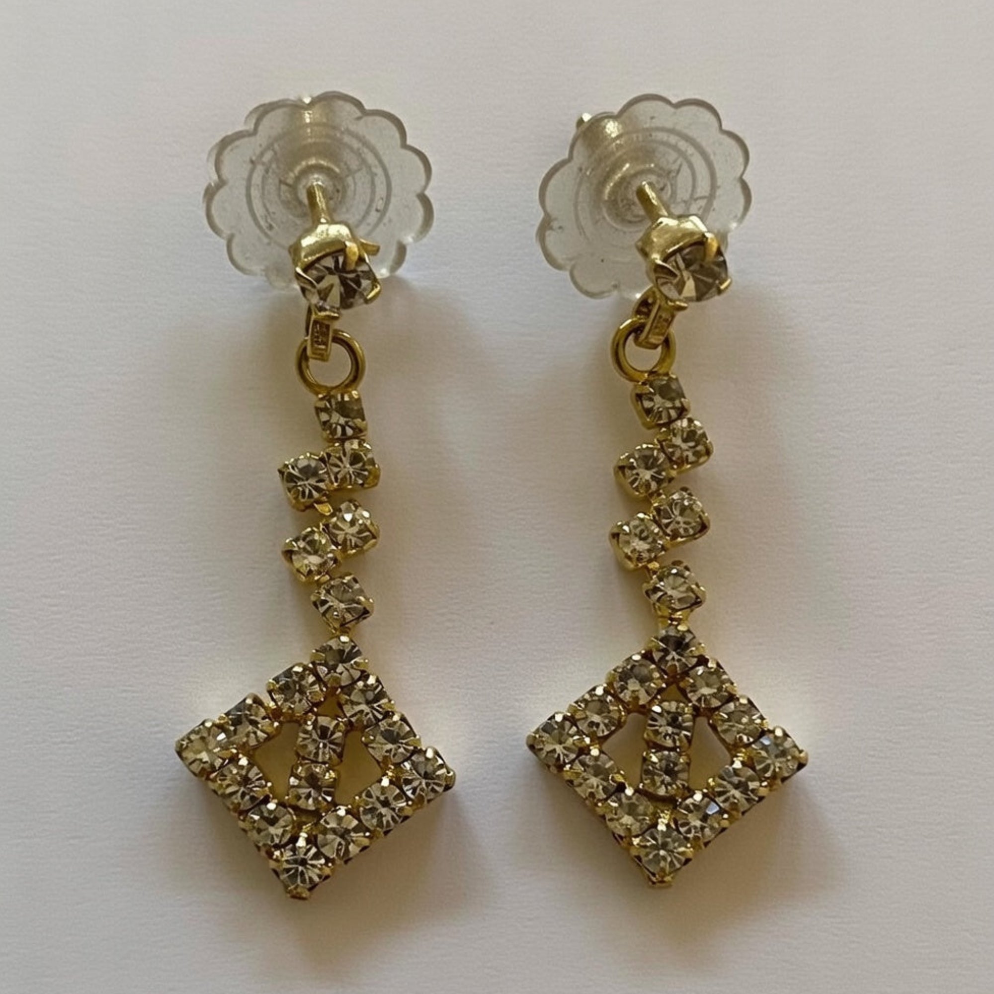 Gold earrings with diamond-like stones on a white background