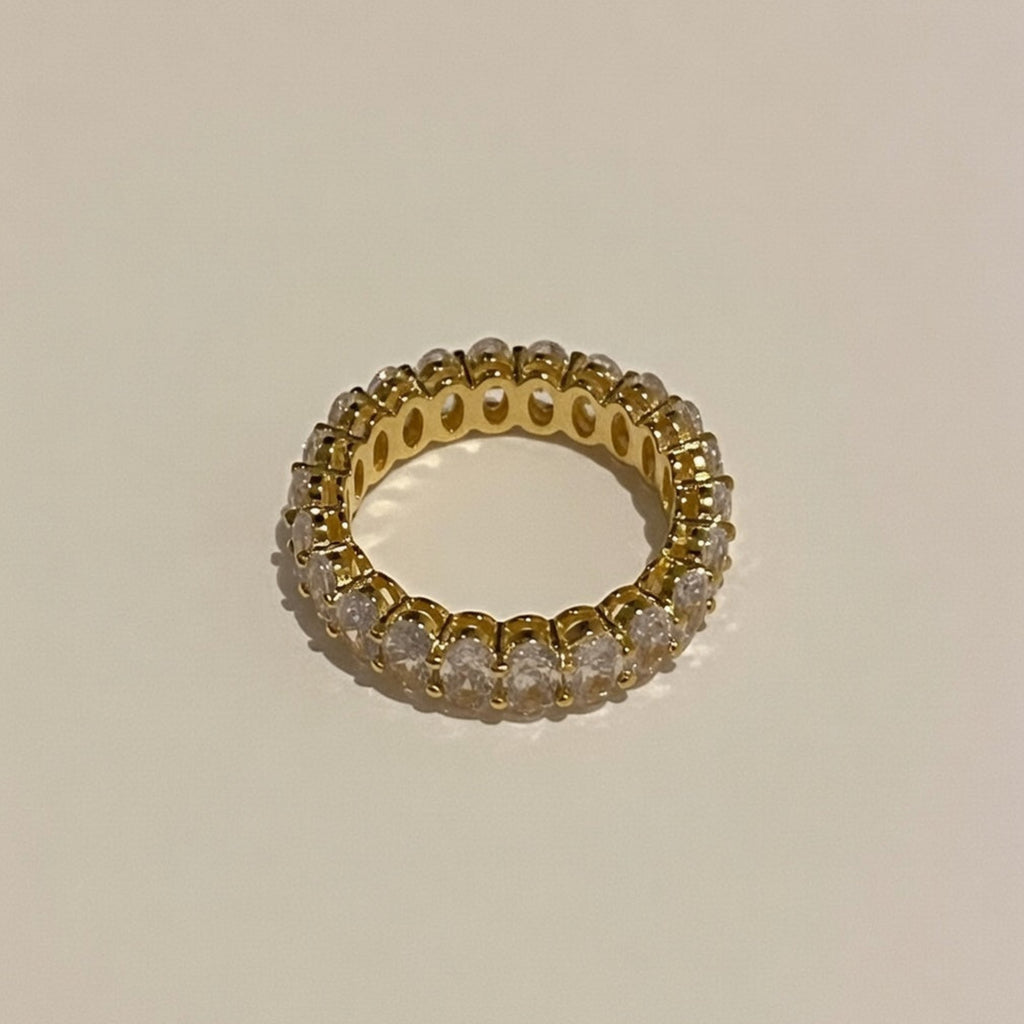 Gold ring with embedded diamonds on a beige background