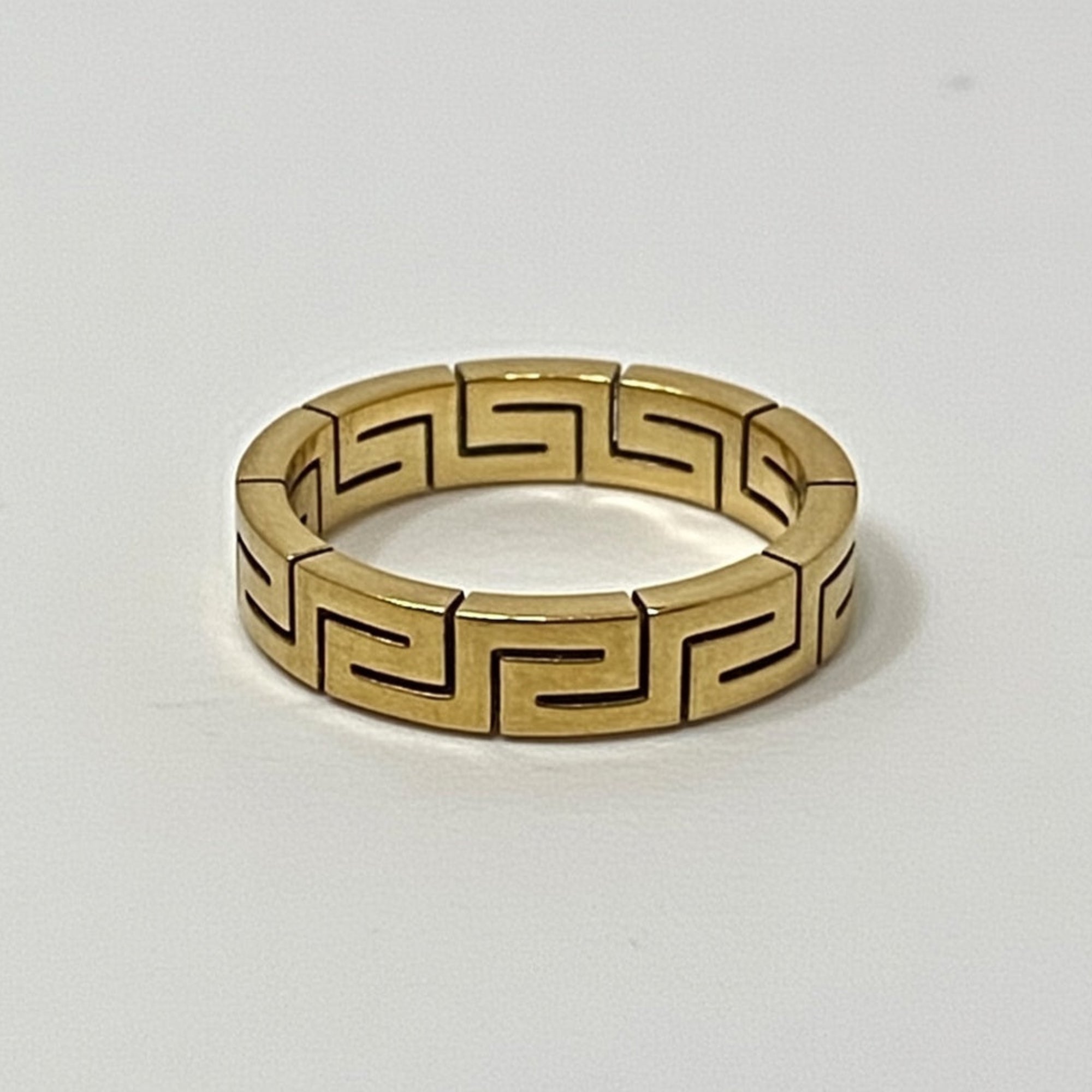 Gold ring with a geometric pattern on a white background