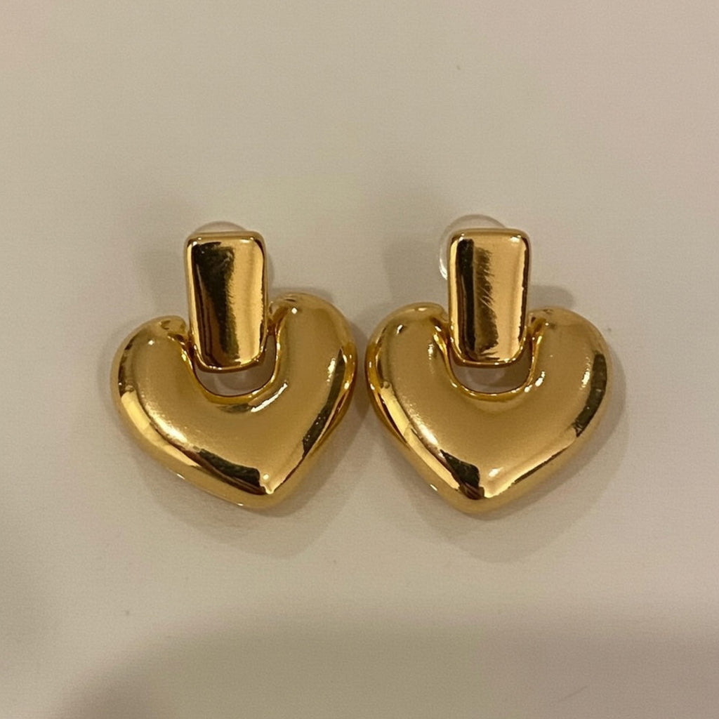 Pair of gold heart-shaped earrings on a light beige background