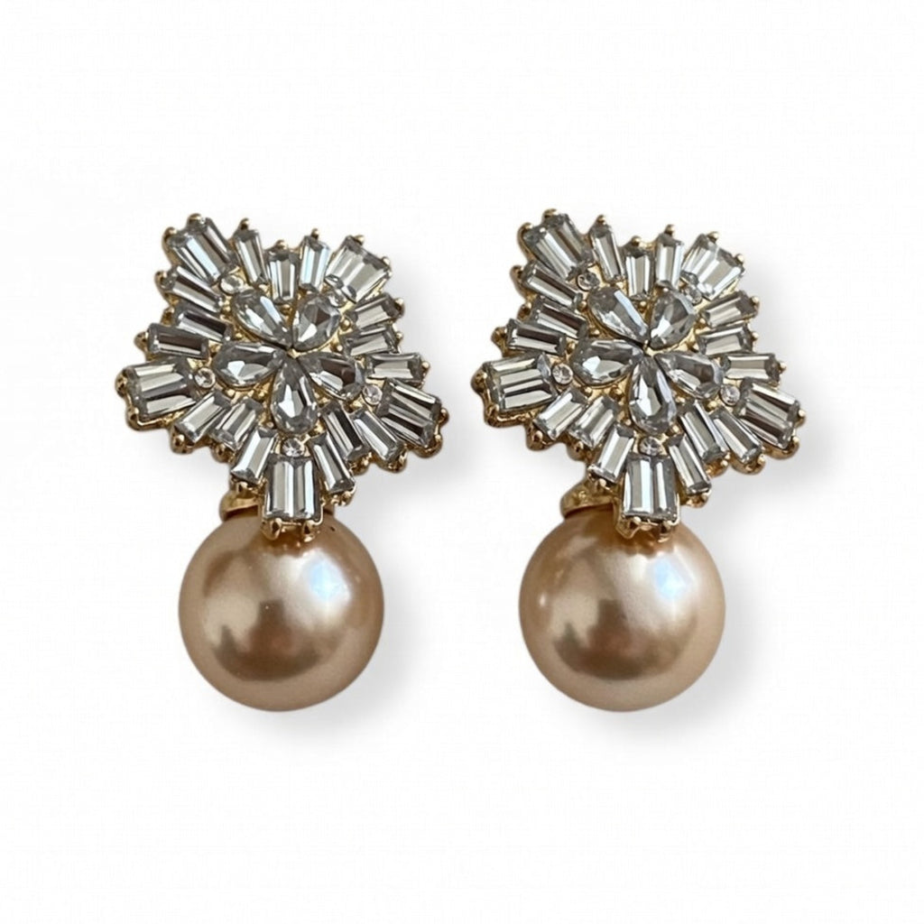 Pair of earrings with crystal embellishments and pearl drops on a white background