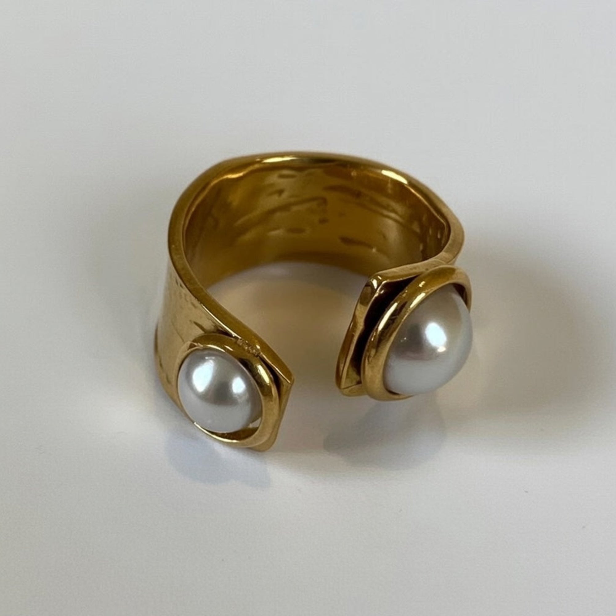 Gold ring with two pearls on a white background