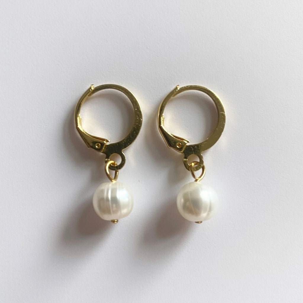 Gold hoop earrings with pearl drops on a white background