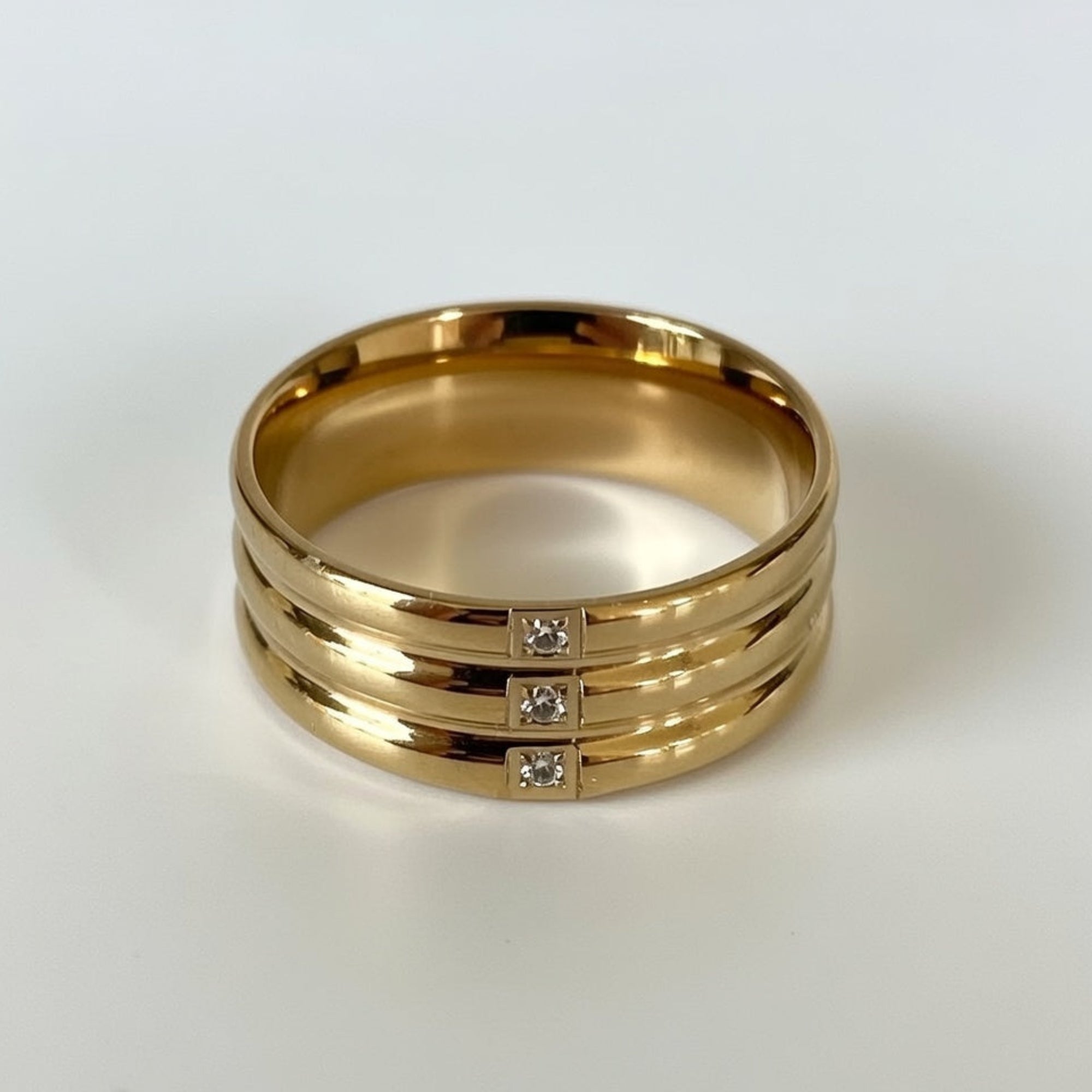 Gold ring with three diamond stones on a white background