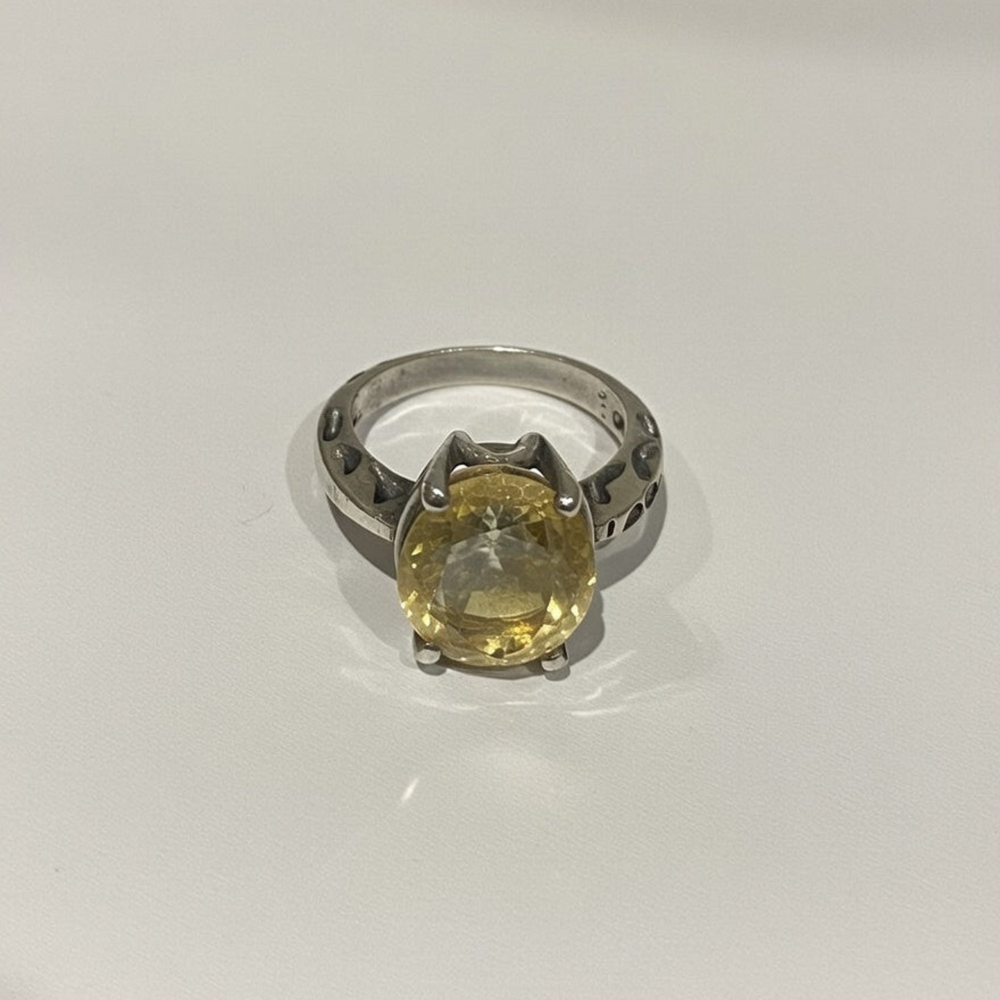 Silver ring with a yellow gemstone on a white background