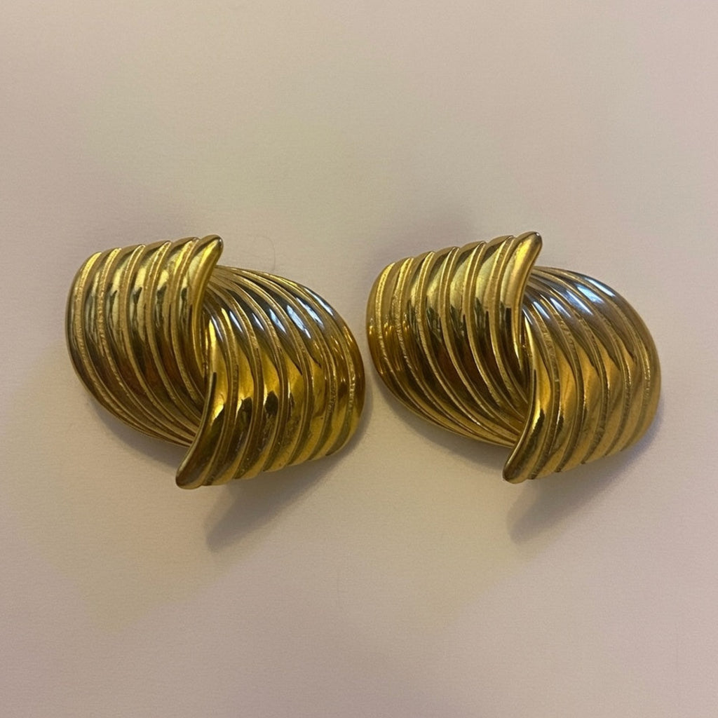 Pair of gold spiral earrings on a light beige background