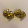 Pair of gold spiral earrings on a light beige background