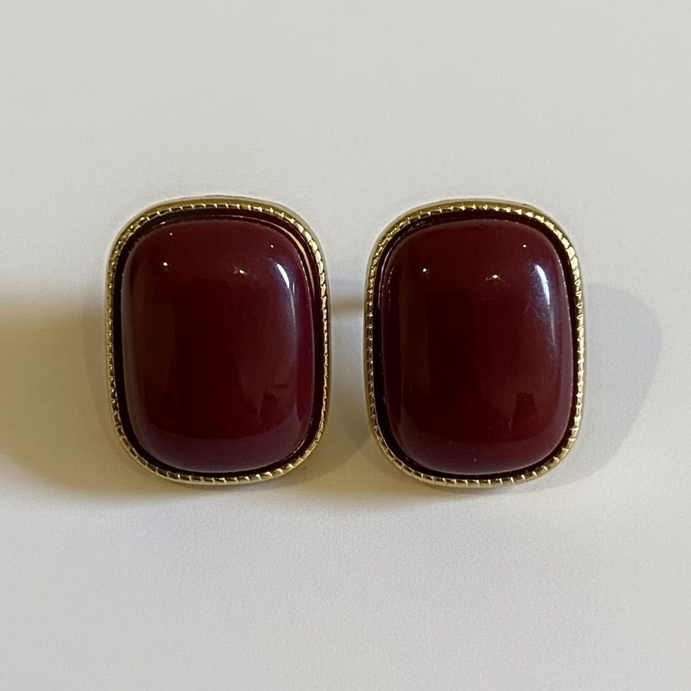 Pair of red earrings with gold frames on a white background