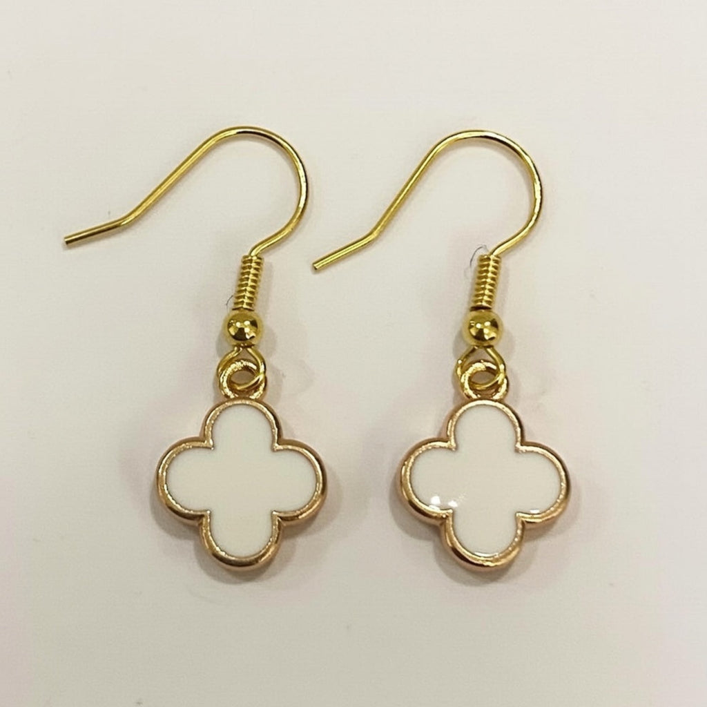 Gold and white clover-shaped earrings on a light background