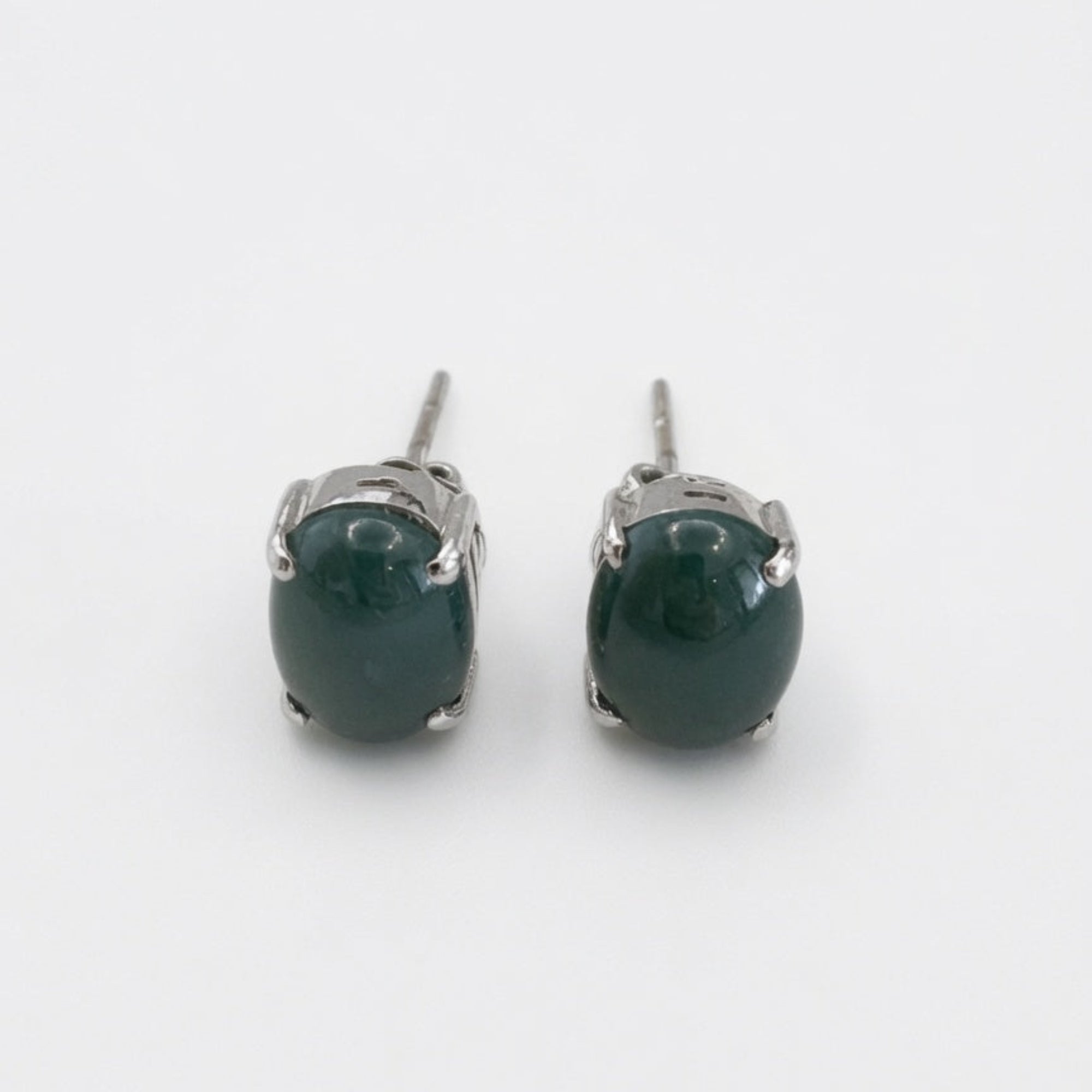 Pair of green gemstone stud earrings on a white background