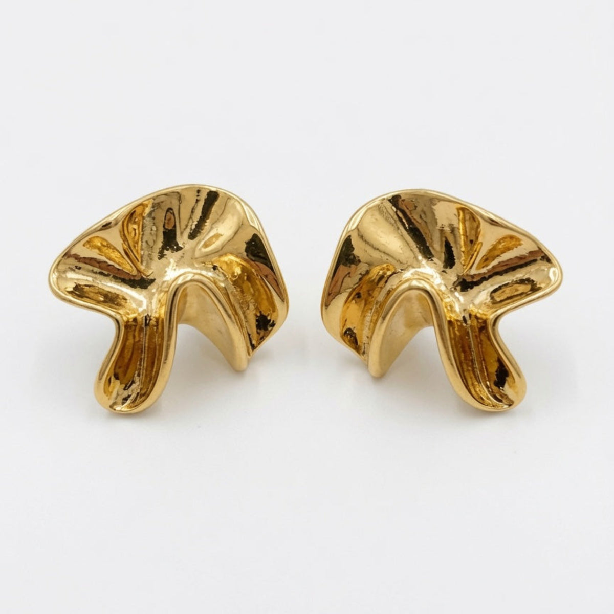 Pair of gold earrings on a white background boheme london