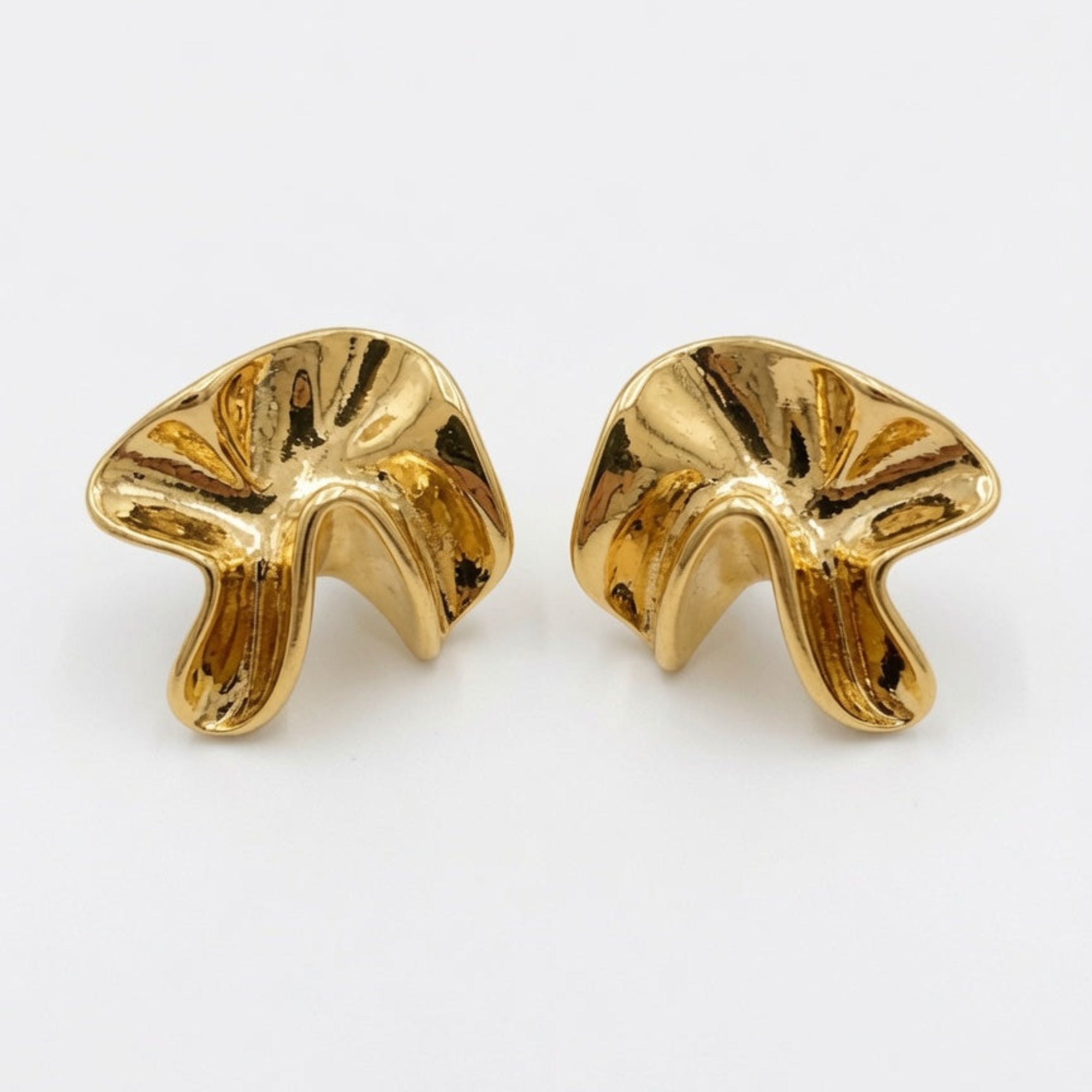 Pair of gold earrings on a white background boheme london